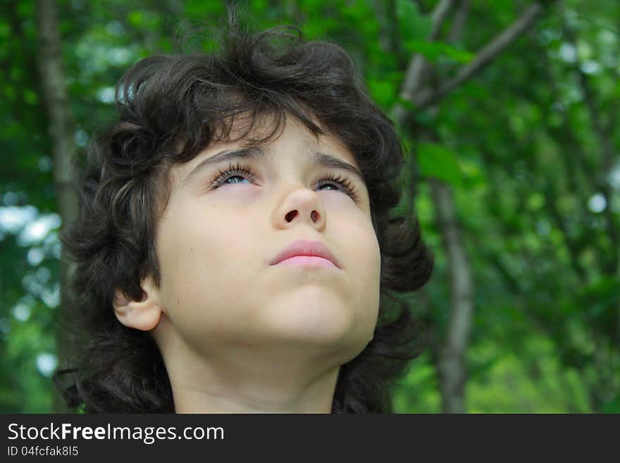 Close portrait of a beautiful boy who looks up to heaven with uplifted head up. Close portrait of a beautiful boy who looks up to heaven with uplifted head up