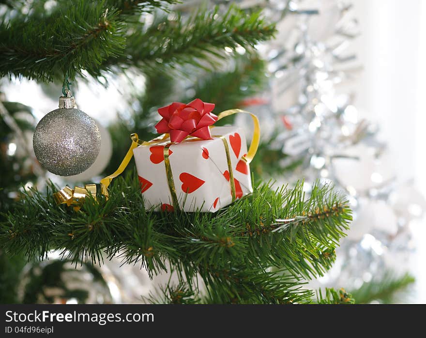 Gift with red bow on christmas tree. Gift with red bow on christmas tree