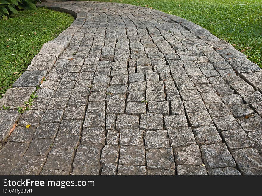 The Stone block walk path in the park with green grass background