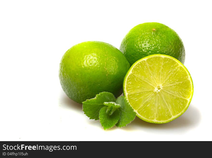 Limes with mint leaves on white.