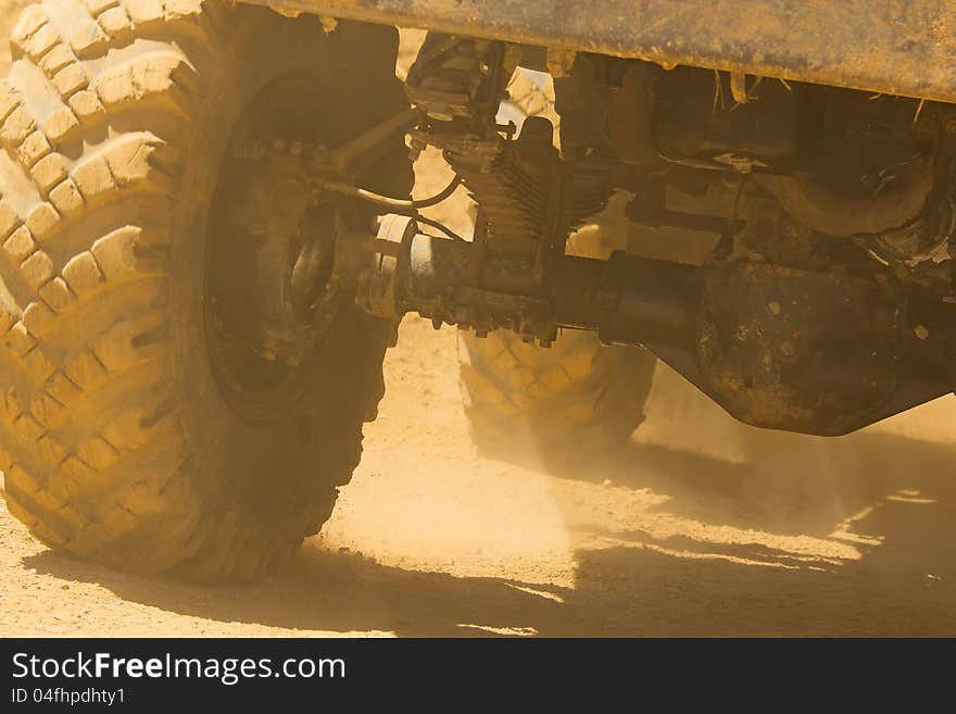 Detailed view of the wheels, tires and truck shaft that goes in the dust of the desert. The rays of light shine through the wheels. Detailed view of the wheels, tires and truck shaft that goes in the dust of the desert. The rays of light shine through the wheels.