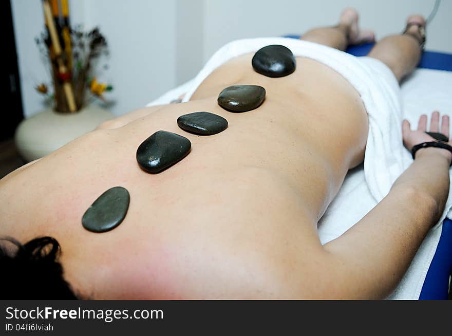 Man relaxing on massage bed with hot stones