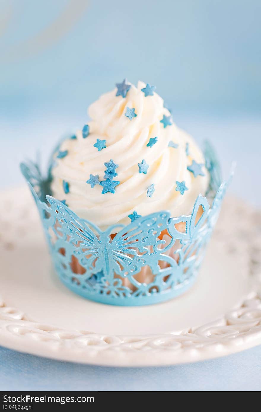 Cupcake with cream and blue decor, selective focus