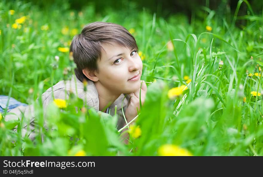 Girl on dandelion on green spring field