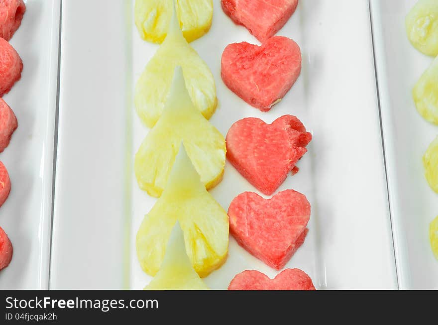 Red heart watermelon with pineapple on white dish