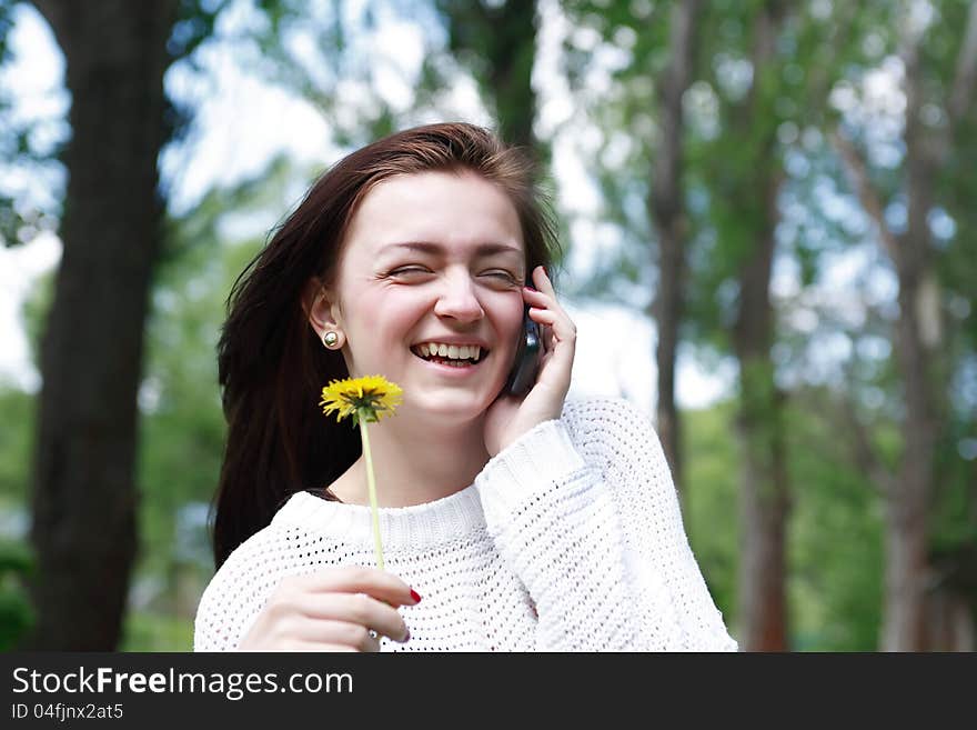 Smiling beauty teenage girl with dandelion talking on mobile phone. Smiling beauty teenage girl with dandelion talking on mobile phone