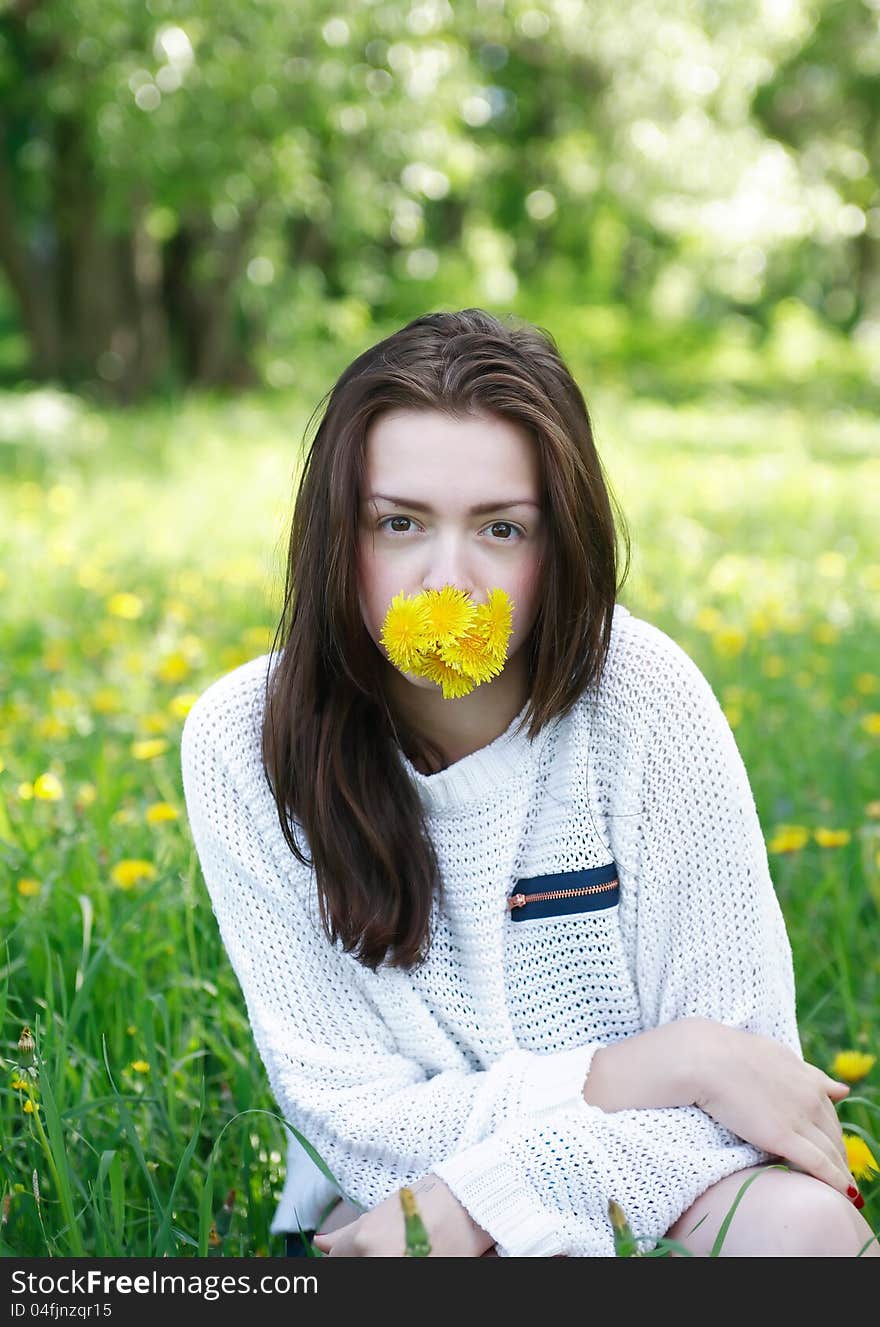 Beauty teenage girl with yellow dandelions in her mouth on green summer background. Beauty teenage girl with yellow dandelions in her mouth on green summer background