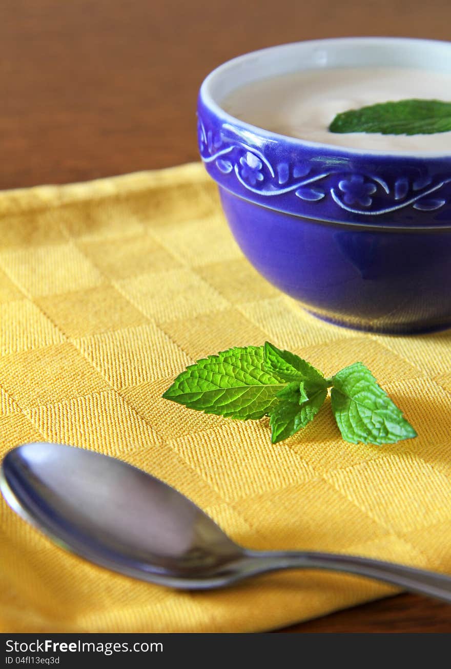 White yogurt in a blue bowl with green mint leaf. White yogurt in a blue bowl with green mint leaf