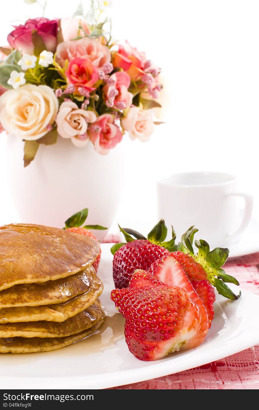 Pancake and strawberry have maple syrup on top with coffee. Pancake and strawberry have maple syrup on top with coffee