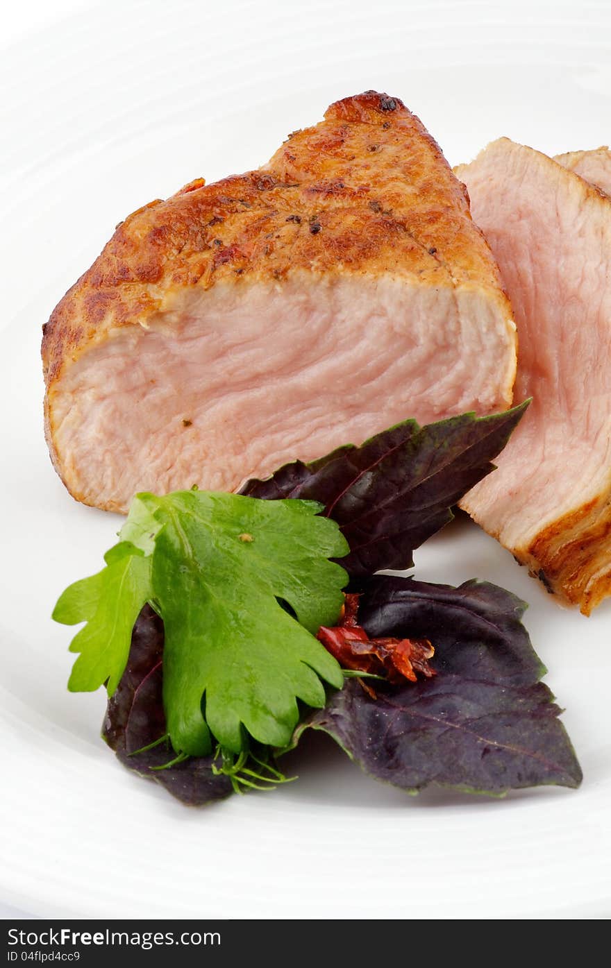 Spicy roast pork with basil and pasley closeup on white background