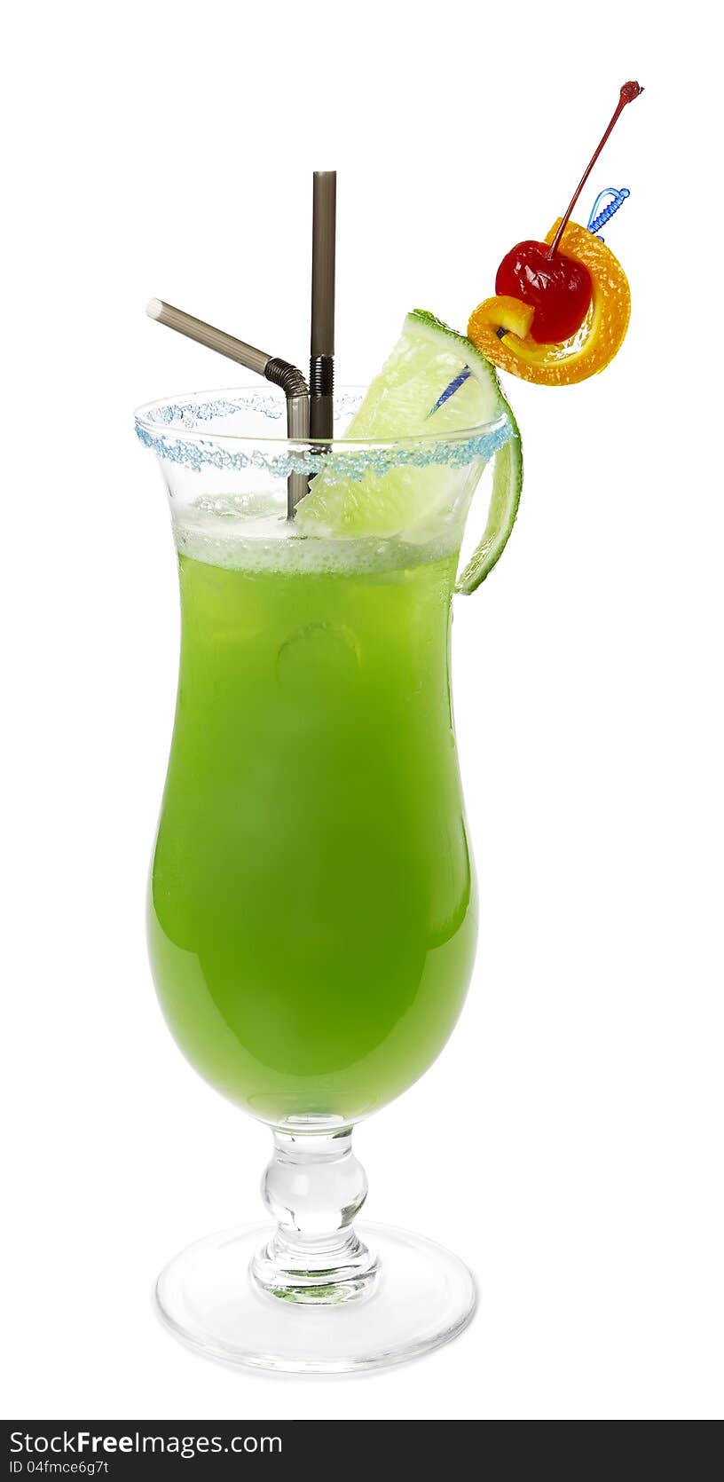 Green alcoholic cocktail with two tubes, lime, orange and red cherry on a skewer. Blue sugar on the edge of the glass