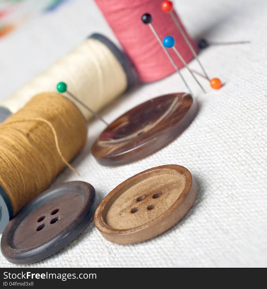 Many bobbin of thread with needle and button on table