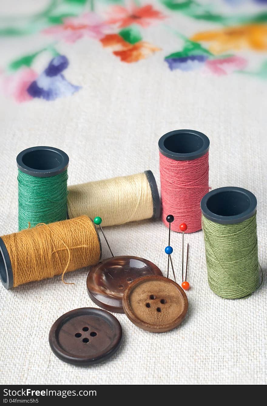 Many bobbin of thread with needle and button on table