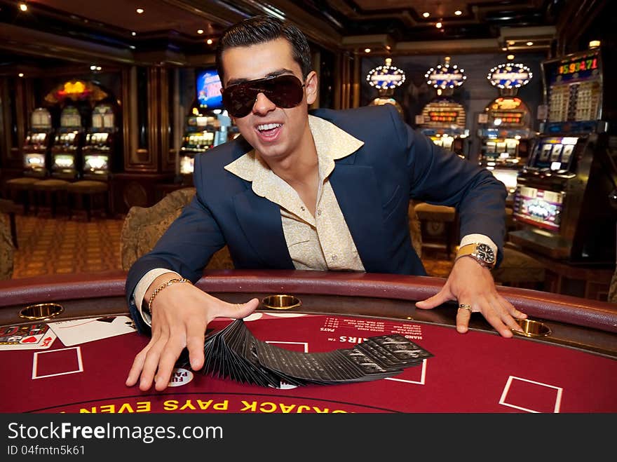 Young man in trendy clothes playing cards in casino. Young man in trendy clothes playing cards in casino