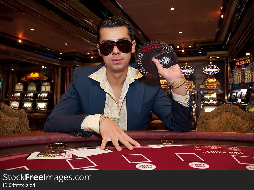 Young man in trendy clothes playing cards in casino. Young man in trendy clothes playing cards in casino