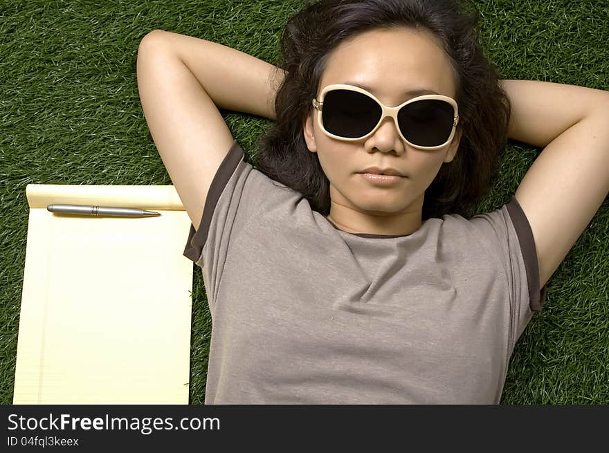 Woman laying on the green grass on the summer. You can put your message on the paper. Woman laying on the green grass on the summer. You can put your message on the paper