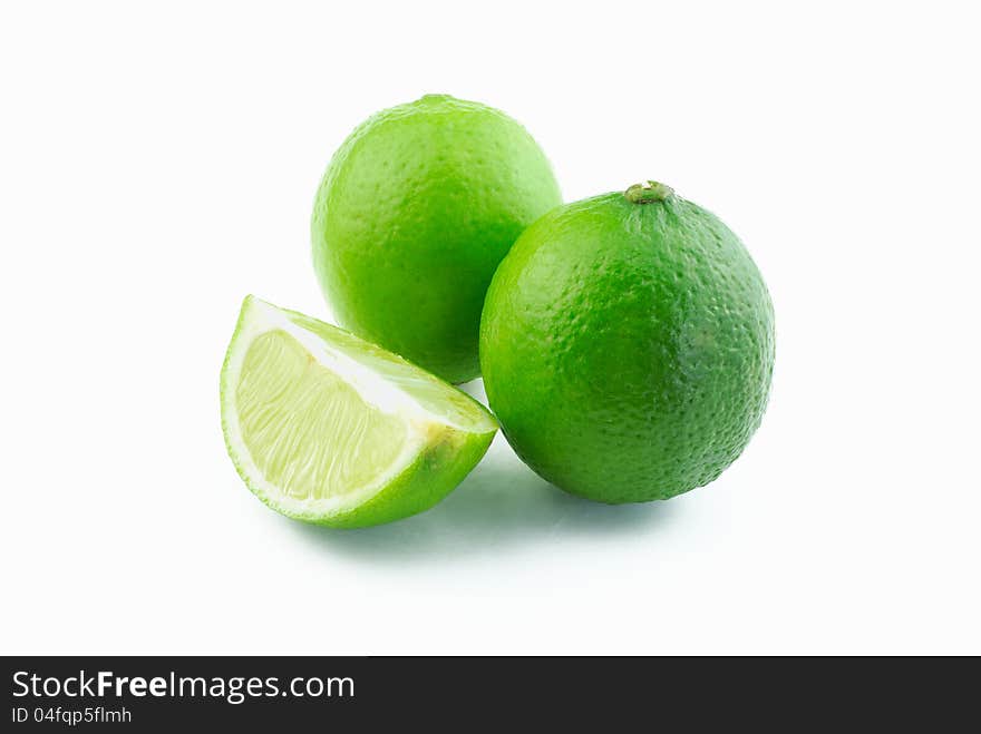 Two green limes and slice on white background