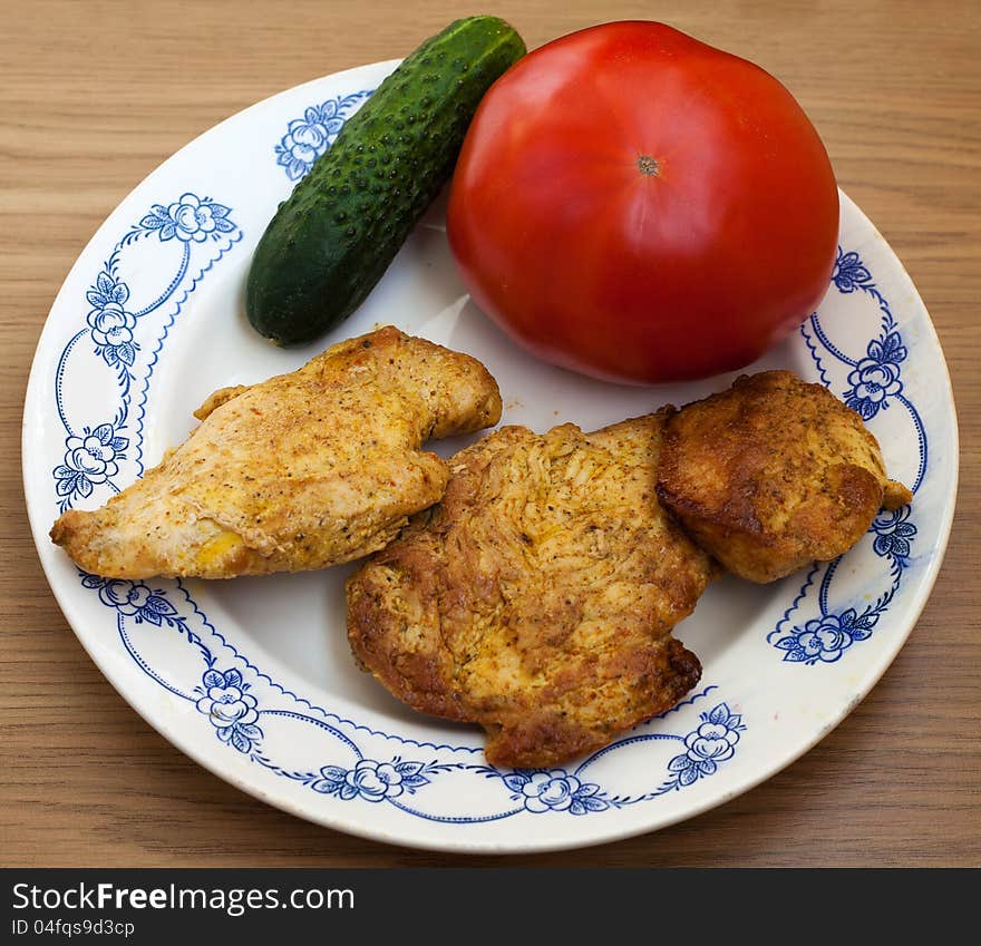 Three pieces of roasted meat with tomato and cucumber on the plate