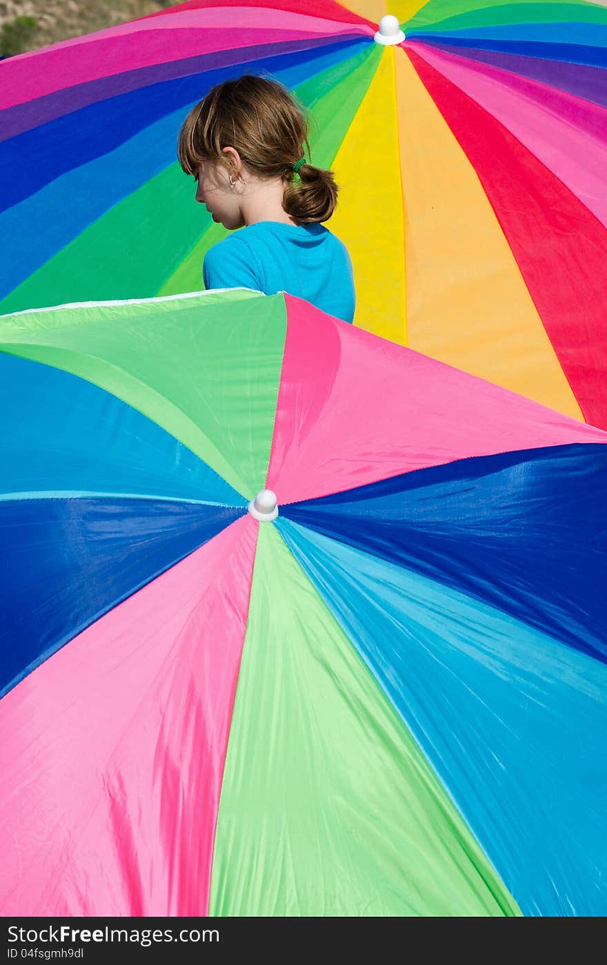 Little girl looks like she is trapped between rainbows of colorful umbrellas. Little girl looks like she is trapped between rainbows of colorful umbrellas