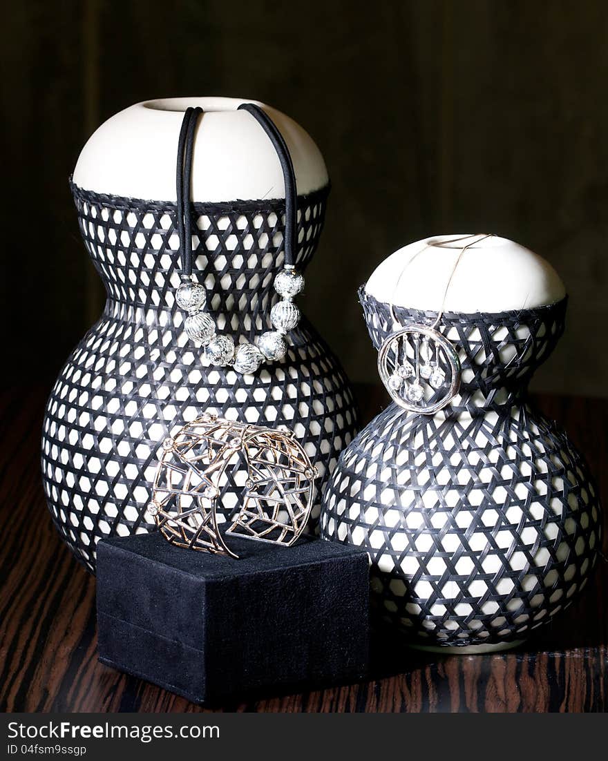 Set of silver necklaces and bracelet shown on ceramic vases