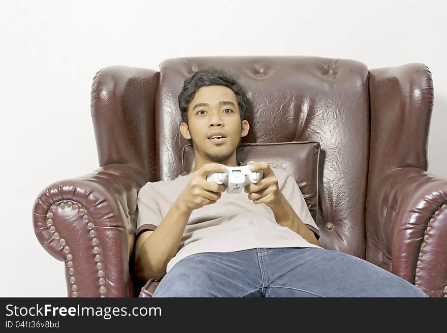 Young male playing video game on the couch on living room