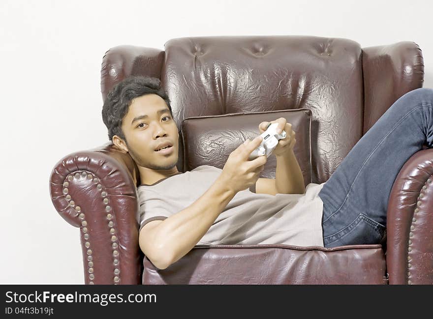 Young male playing video game on the couch on living room