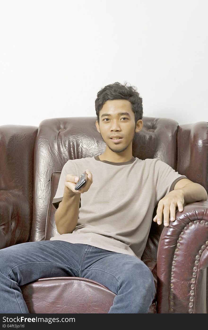 Young man watching tv from his couch and holding remote control