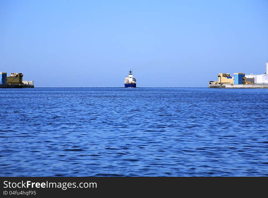 Panorama view with cargo ship moving from harbour to open sea. Panorama view with cargo ship moving from harbour to open sea