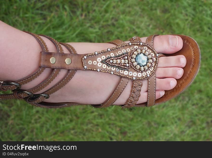 Girl’s feet in a summer sandal with grass int he background. Girl’s feet in a summer sandal with grass int he background