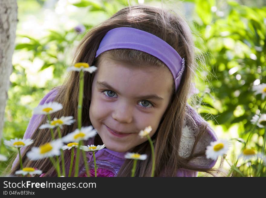 Beautiful little girl among camomiles in a garden. Beautiful little girl among camomiles in a garden