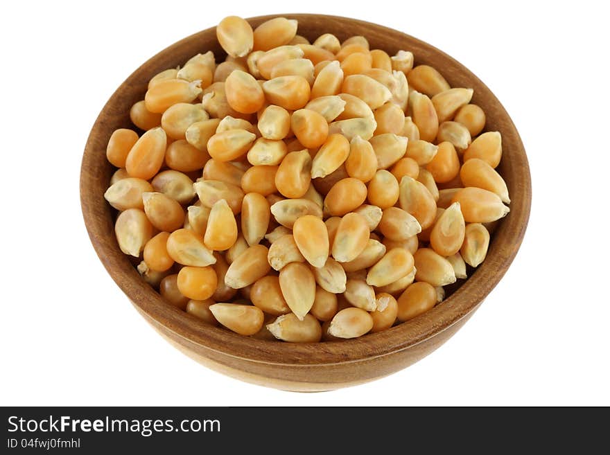 A wooden bowl full of dried yellow corn kernels, isolated on white background