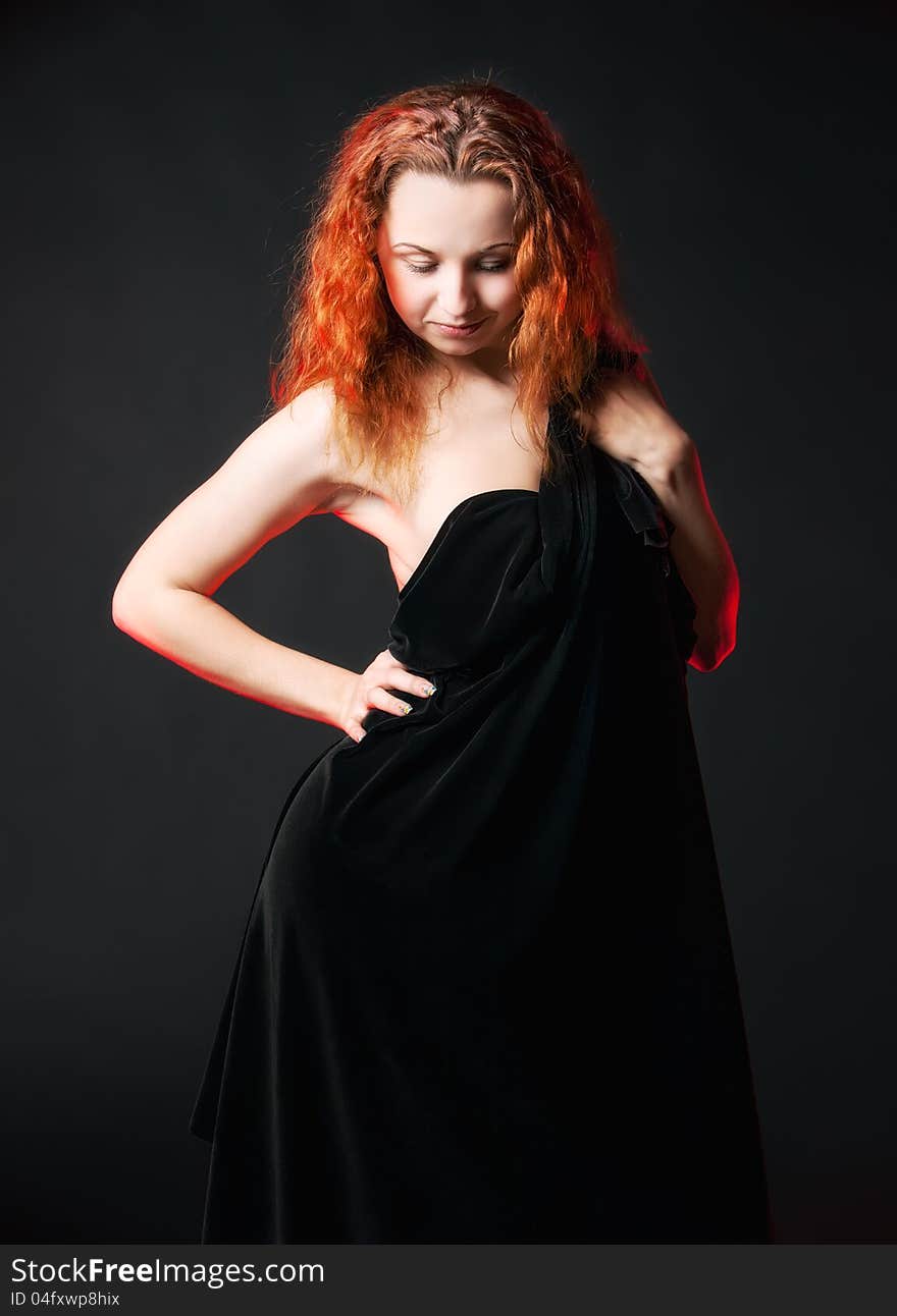 Redhead girl in black posing on a dark background