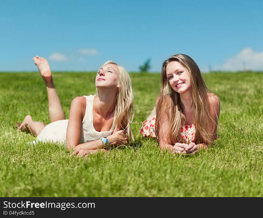 Two girlfriends on a grass field. Two girlfriends on a grass field