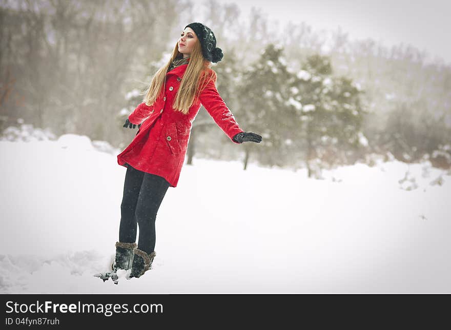 Happy girl with cap and gloves playing with snow