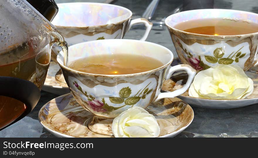 Pouring tea from porcelain tea-kettle into cup.