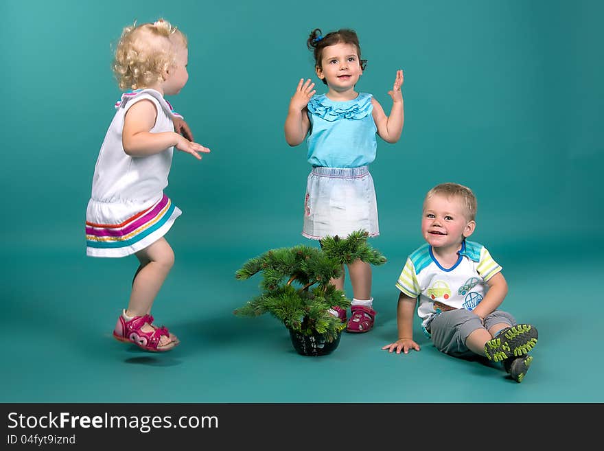 Three children playing on a turquoise background in studio