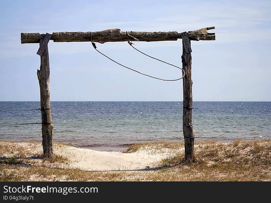 View of the beach behind the arch of wooden logs. View of the beach behind the arch of wooden logs