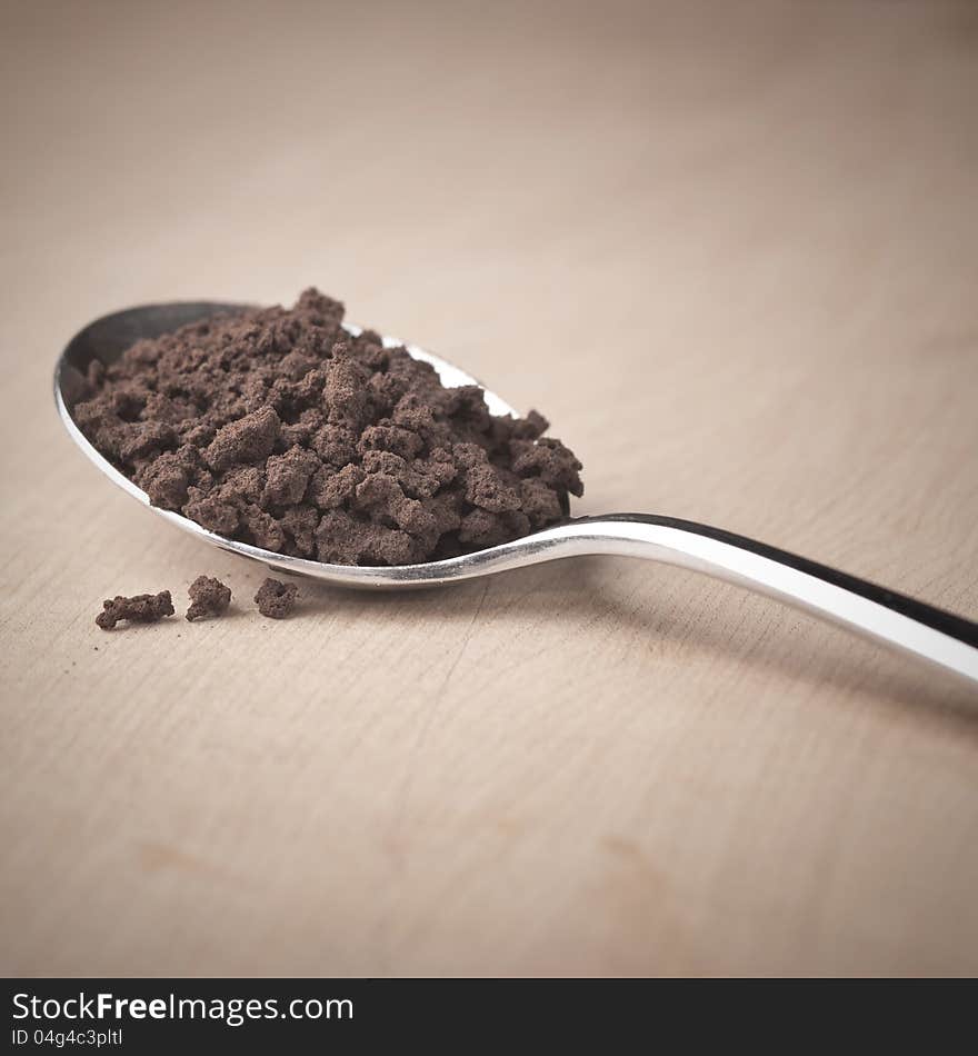 Instant coffee in the spoon on wooden table