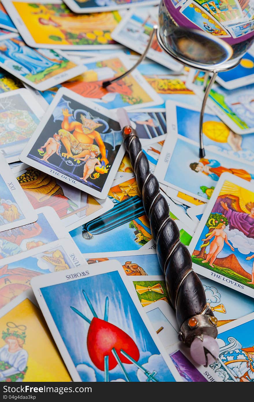 Many mixed tarot cards on the table with a crystal ball and magic wand (vertical). Many mixed tarot cards on the table with a crystal ball and magic wand (vertical).