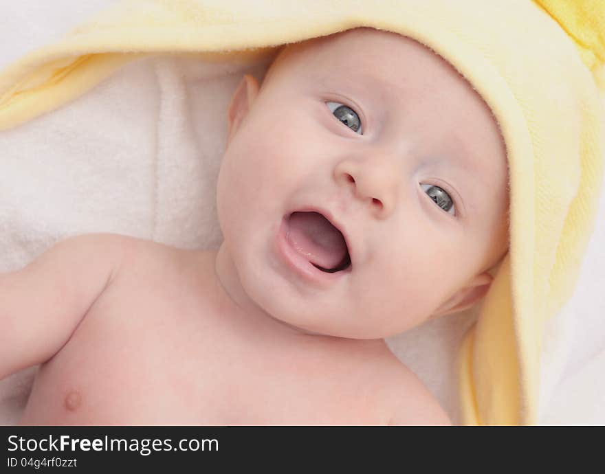 Sweet child under yellow towel on white background