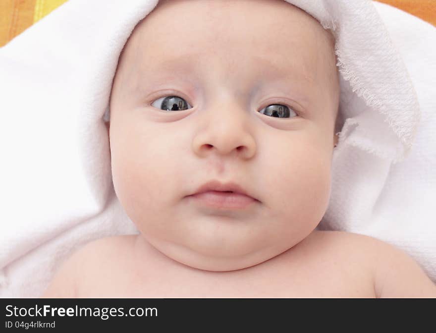 Sweet child under yellow towel on white background