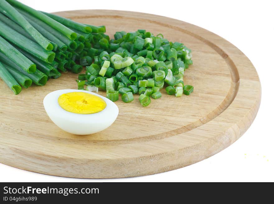 Green onions and half of the eggs on a wooden kitchen board