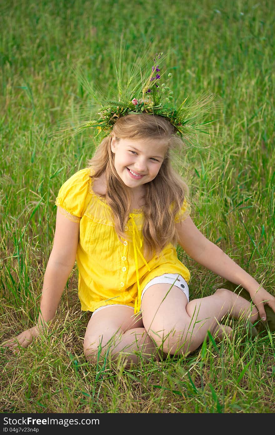 Beautiful little girl on the meadow. A wreath of wheat ears and wild flowers is on her blonde hair. Beautiful little girl on the meadow. A wreath of wheat ears and wild flowers is on her blonde hair