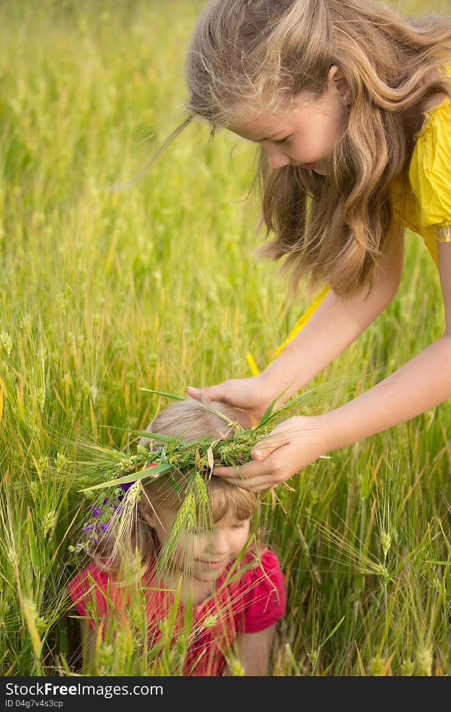 The older sister wears a wreath of the wheat on the head of the younger sister. The older sister wears a wreath of the wheat on the head of the younger sister