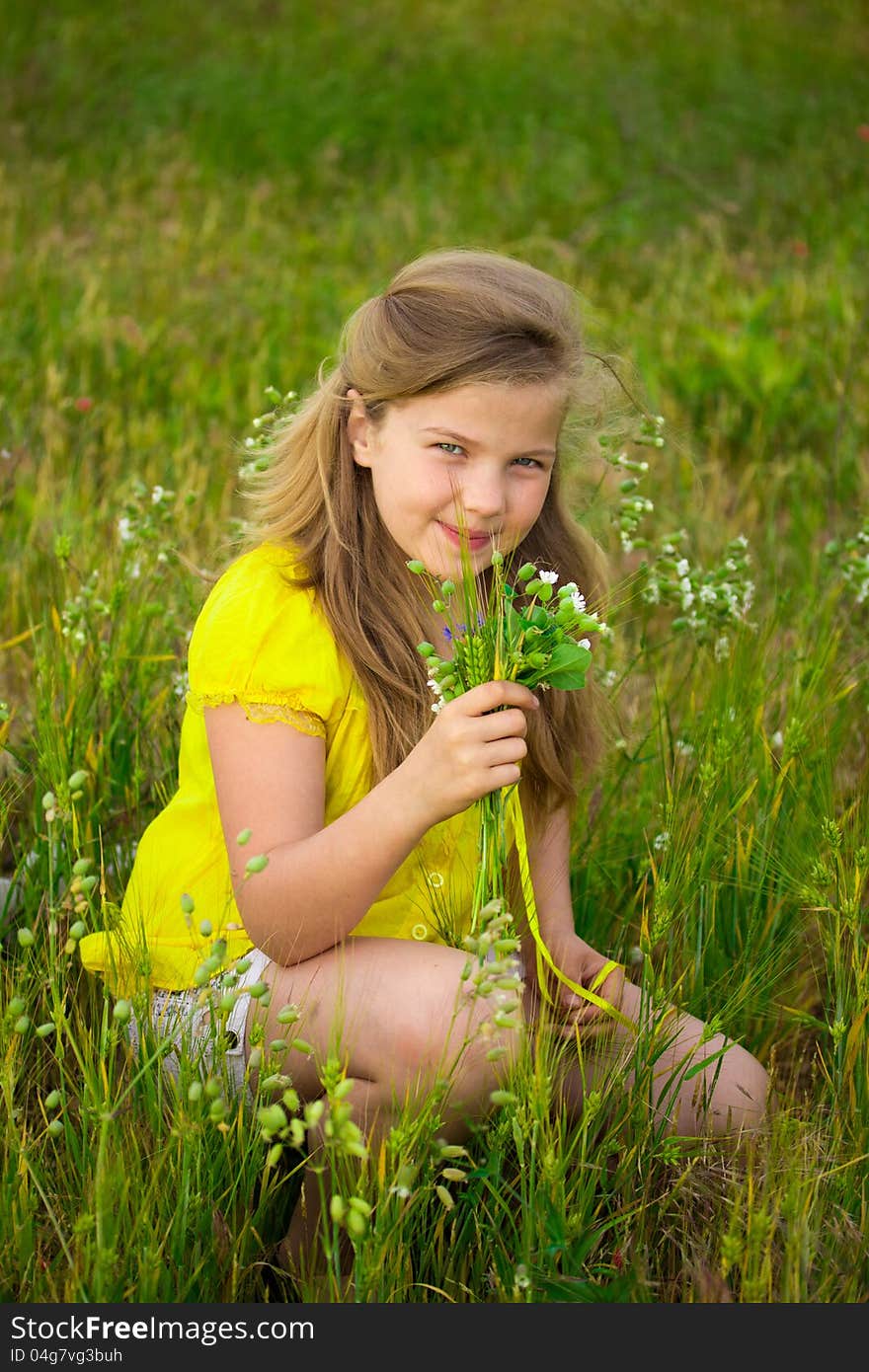 Sweet blonde little girl smelling field flowers on the meadow. Sweet blonde little girl smelling field flowers on the meadow