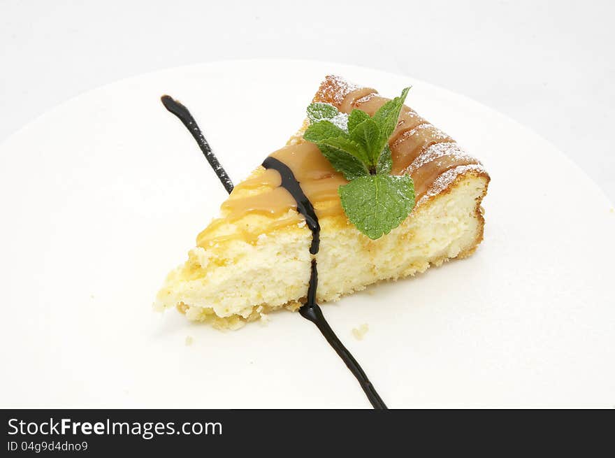 A piece of cheese cake decorated with mint leaves. A piece of cheese cake decorated with mint leaves