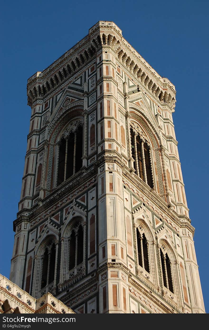 The bell tower of the Santa Maria Del Fiore cathedral (the Duomo) of Florence, Italy, set against a deep blue sky, which makes its white, green and pink marble sparkle in the sun. The bell tower of the Santa Maria Del Fiore cathedral (the Duomo) of Florence, Italy, set against a deep blue sky, which makes its white, green and pink marble sparkle in the sun.