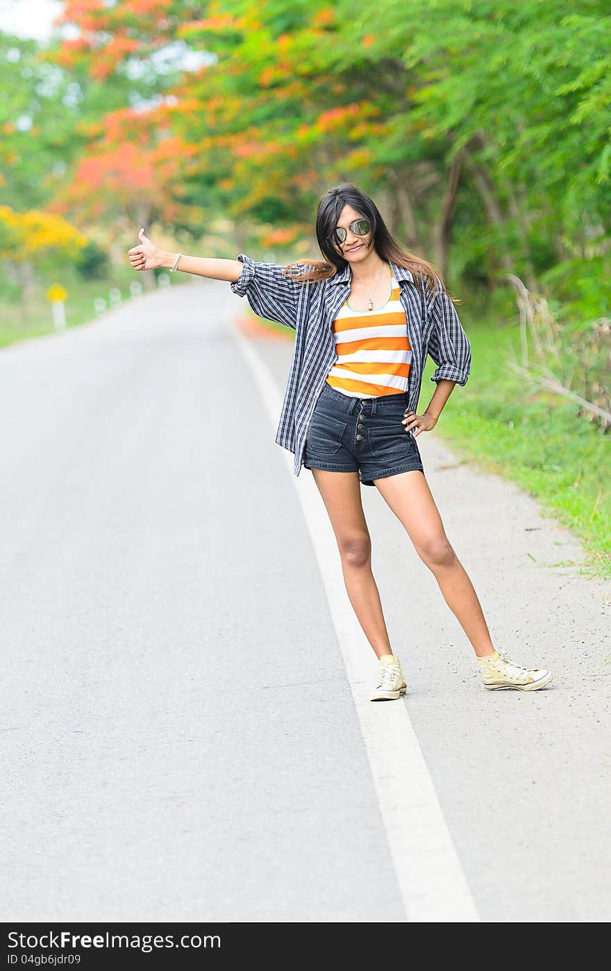 An asian attractive delight girl travelling by thump up with casual wear on blur forest background. An asian attractive delight girl travelling by thump up with casual wear on blur forest background