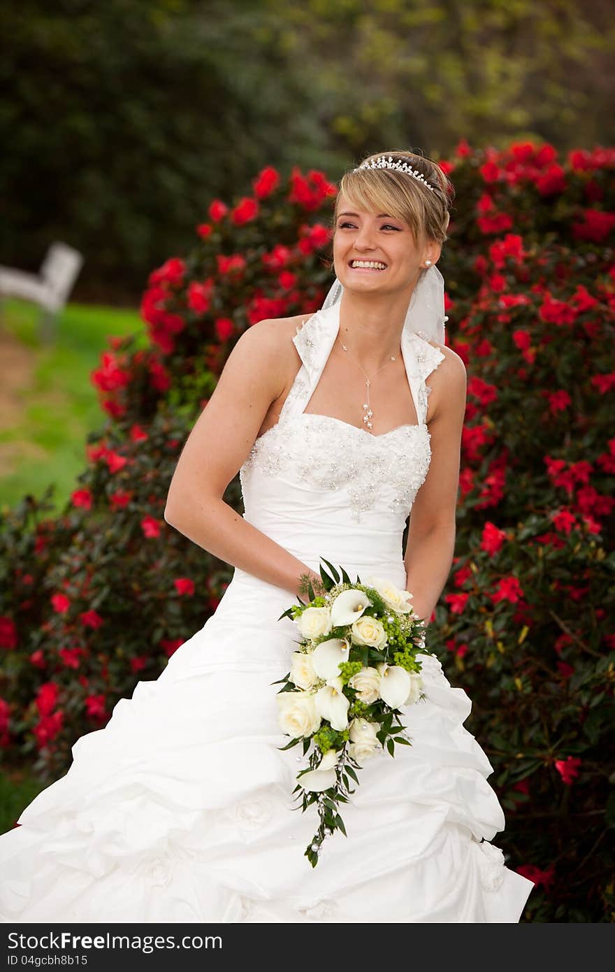 Young bride is laughing and standing in front of nice red roses and holding a nice yellow roses bouquet in her hands. she starts dancing after her wedding ceremony. Young bride is laughing and standing in front of nice red roses and holding a nice yellow roses bouquet in her hands. she starts dancing after her wedding ceremony