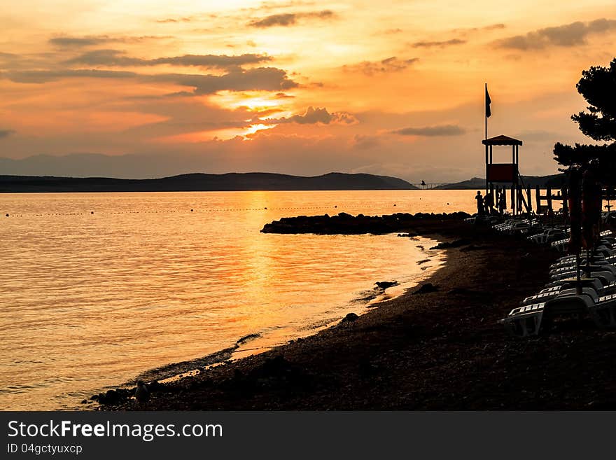 Evening sunset on beach with sun beds and guardian towers